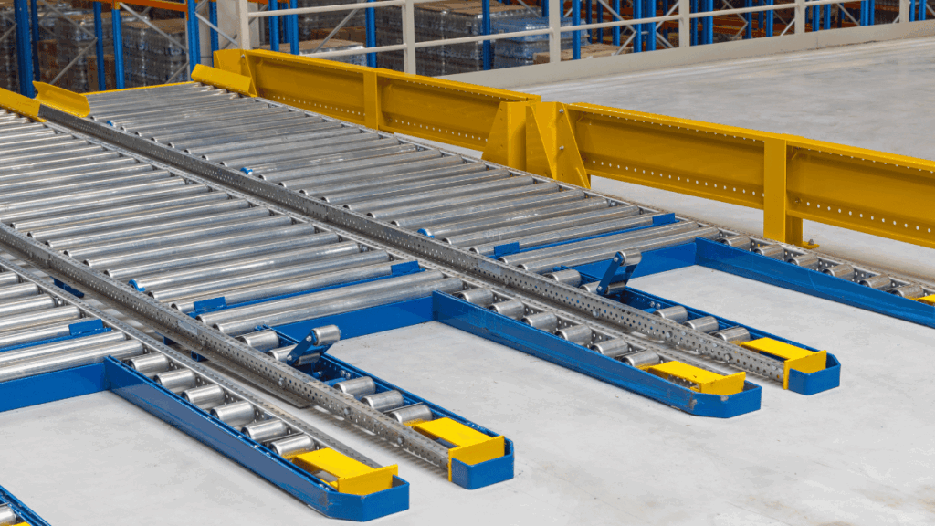Industrial conveyor rollers and metal rails with yellow safety barriers in a warehouse setting, designed for efficient material handling and seamless automation interface.